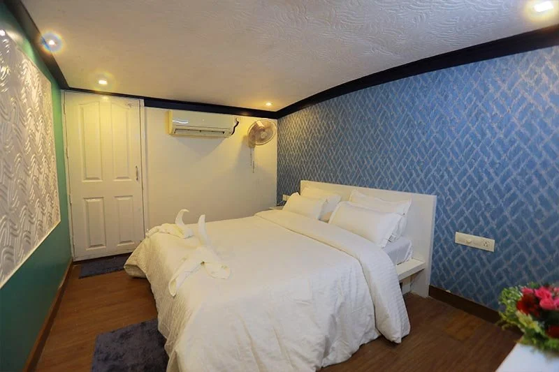 Premium AC stateroom with blue geometric chevron wallpaper, contemporary white headboard, and climate control