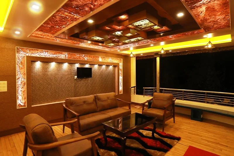 Luxury air-conditioned living lounge with illuminated amber onyx ceiling, leather sofa seating, and wall TV